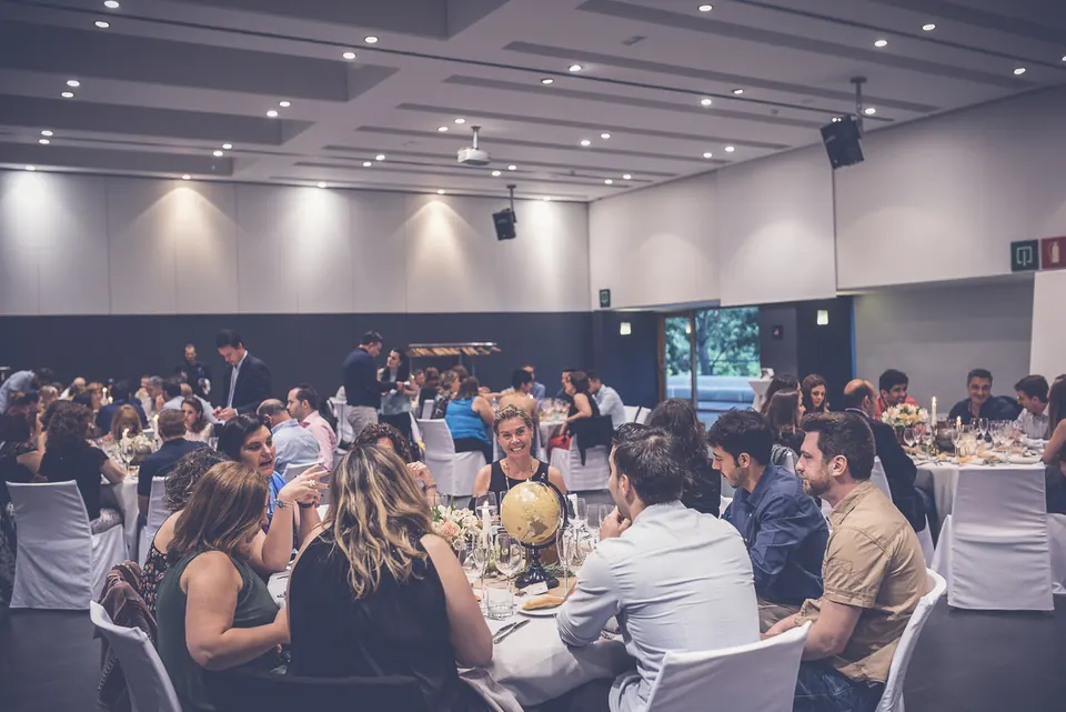 Salón histórico con techos altos, lámparas de araña y mesas montadas para una cena de empresa